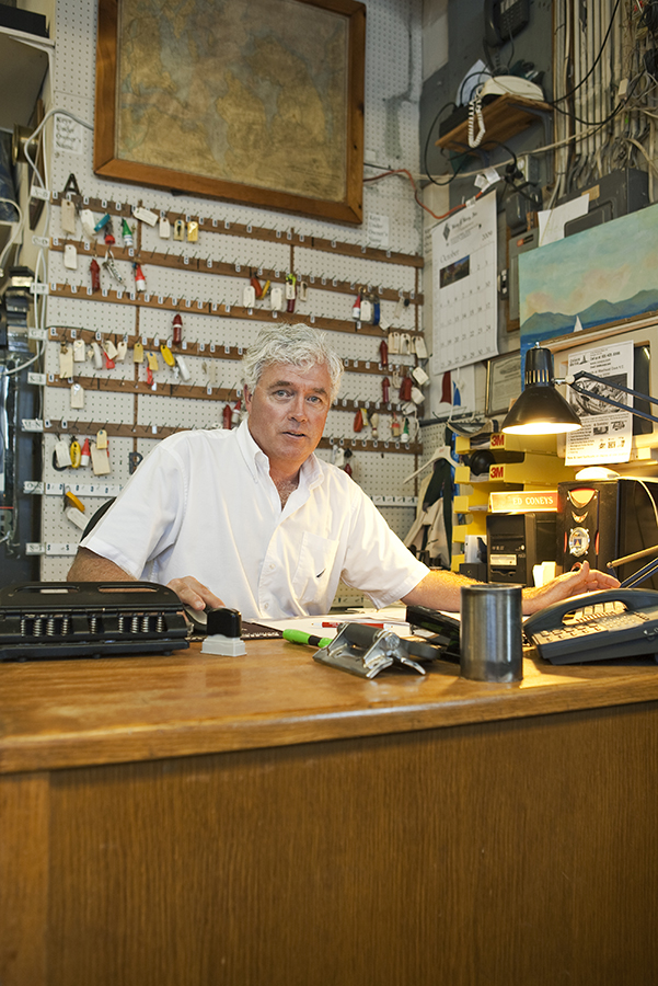 One of the owners of a marina in Huntington, New York sits behind his desk and in front of rows of keys